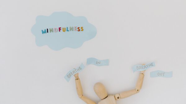 Wooden mannequin with “Mindfulness” and “Breathe In Breathe Out” text on a minimalistic background.