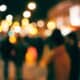 Blurry city street at night with colorful bokeh and silhouettes of people.